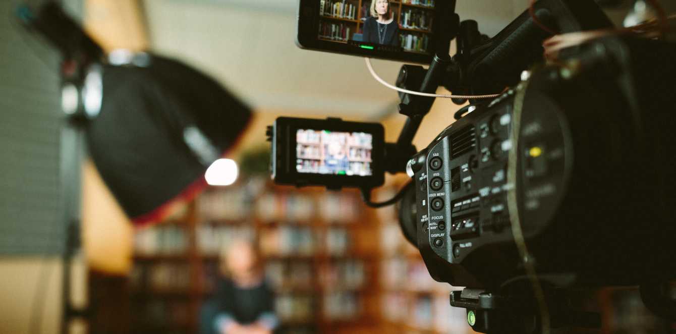 Person sitting in front bookshelf during filming