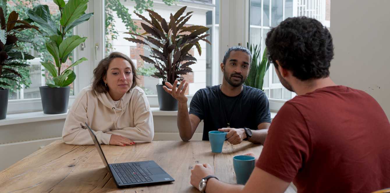 Three people siting at a table having a discussion